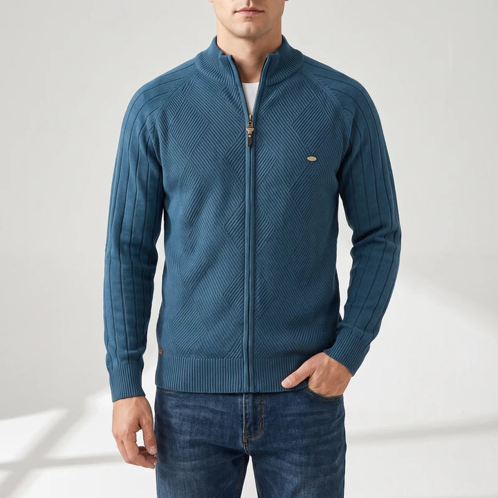 Man wearing a teal blue zip-up knit sweater with a textured diagonal pattern on the body and vertical ribs on the sleeves.