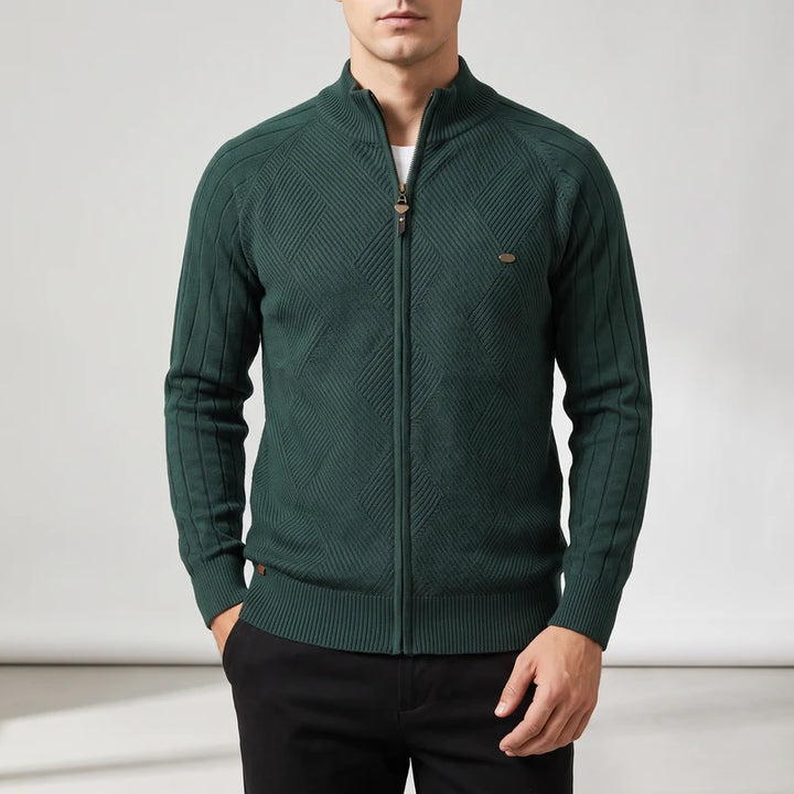 Man wearing a dark green knit zip-up sweater with a diagonal geometric pattern and ribbed sleeves.