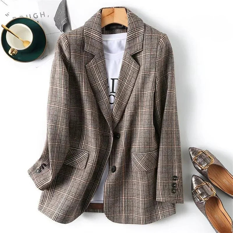 Brown and beige plaid blazer with notched lapels and two patch pockets, hanging on a wooden hanger with a white t-shirt.