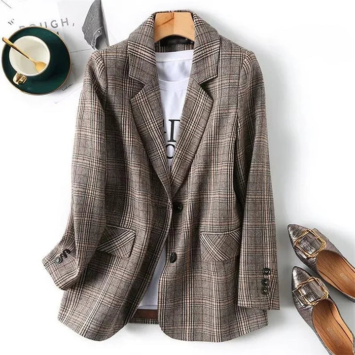 Brown and beige plaid blazer with notched lapels and two patch pockets, hanging on a wooden hanger with a white t-shirt.