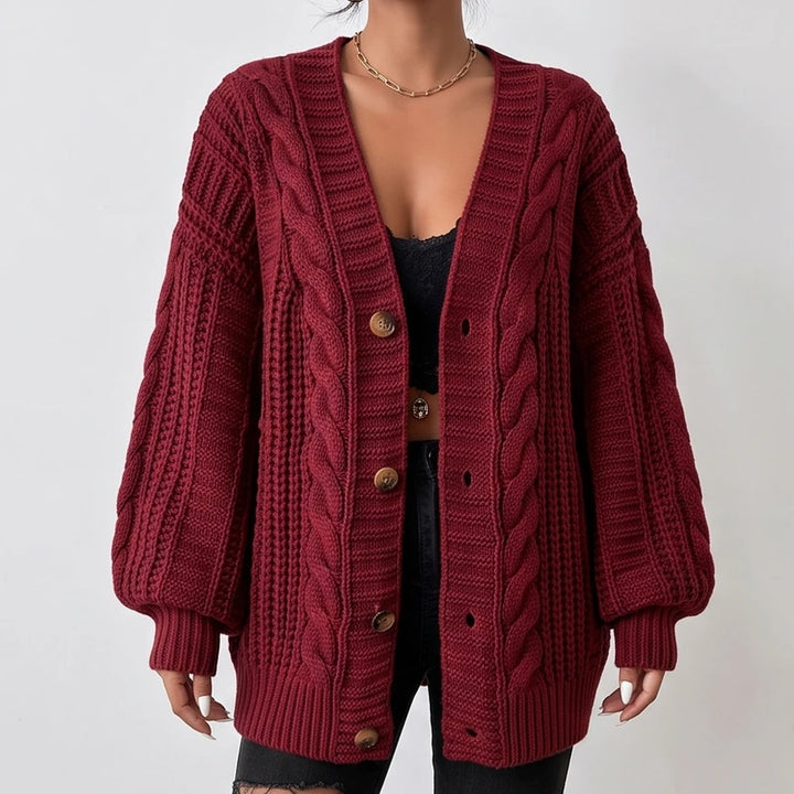 Woman wearing a dark red cable knit oversized cardigan with wooden buttons and long puff sleeves.