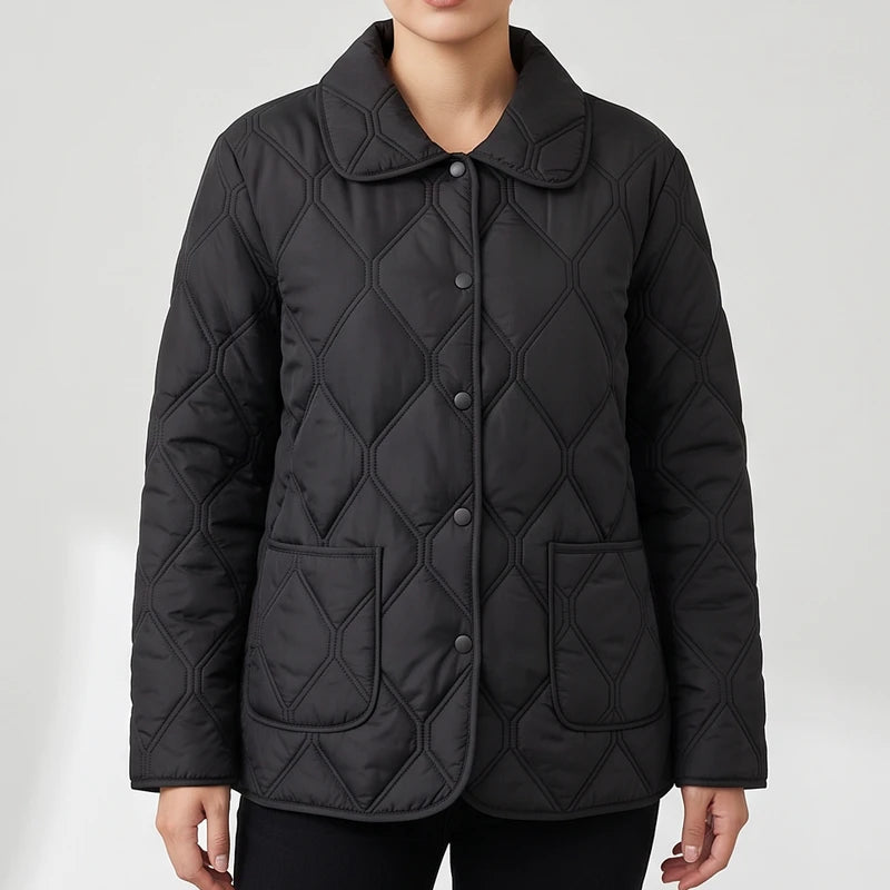 Woman wearing a black quilted jacket with a pointed collar, snap buttons, and two patch pockets on a white background.