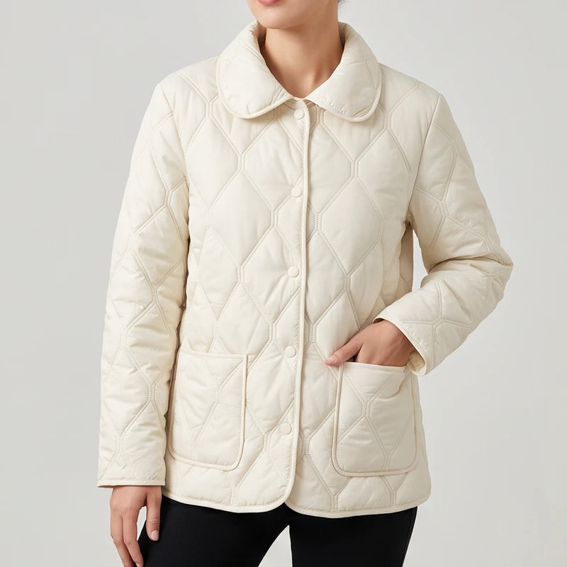 Woman wearing a cream quilted jacket with a round collar, front buttons, and a patch pocket.