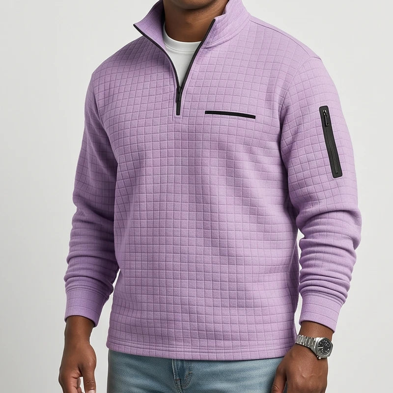 Man wearing a lavender quilted pullover with a black quarter-zip, horizontal chest pocket, and zippered sleeve pocket.