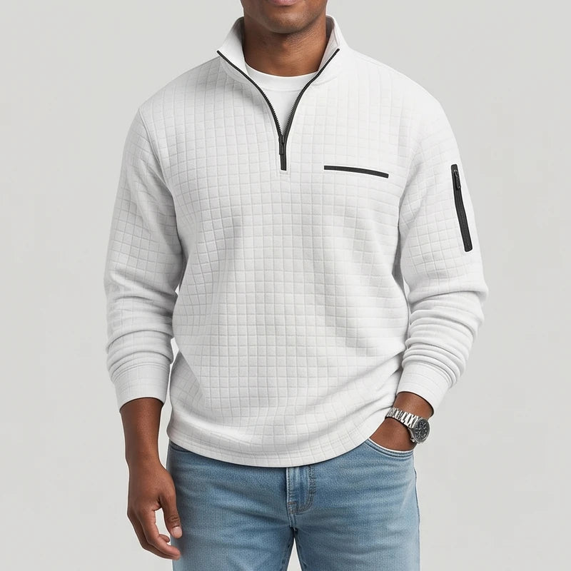 Man wearing a light grey textured quarter-zip pullover with a black zipper, chest pocket, and sleeve pocket.