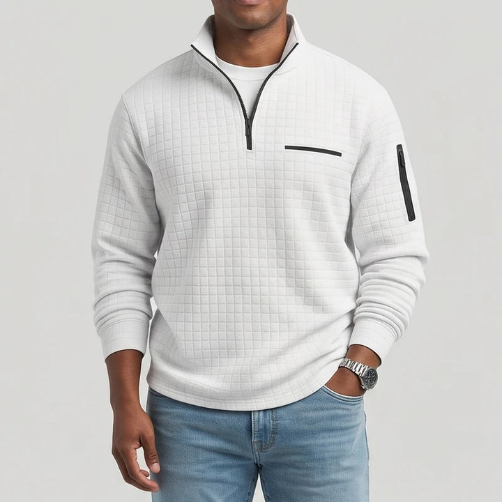Man wearing a light grey textured quarter-zip pullover with a black zipper, chest pocket, and sleeve pocket.