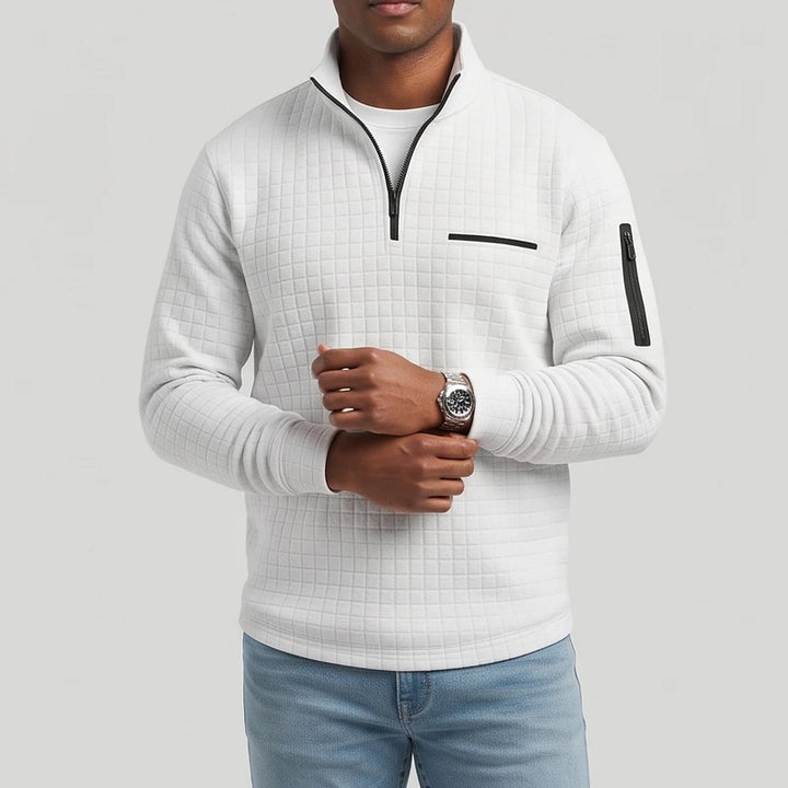 Man wearing a light gray textured quarter-zip pullover with black zippers and a chest pocket, adjusting a watch.