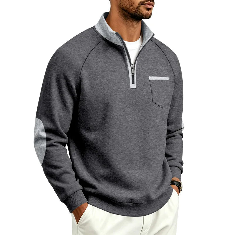 Man wearing a charcoal grey quarter-zip pullover with light grey collar, elbow patches, and chest pocket trim.