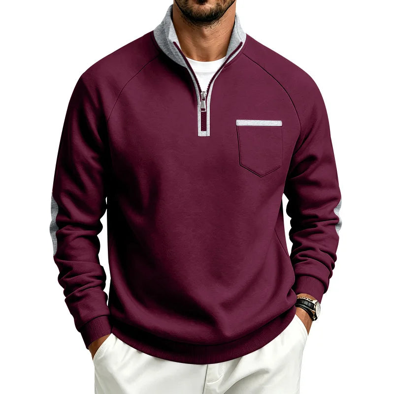 Man wearing a maroon quarter-zip sweatshirt with a gray collar, silver zipper, chest pocket, and gray sleeve stripes.