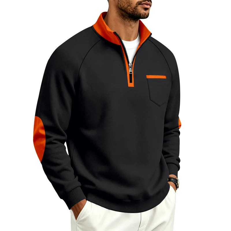 Man wearing a black quarter-zip long-sleeve top with bright orange collar, elbow patches, and chest pocket trim.