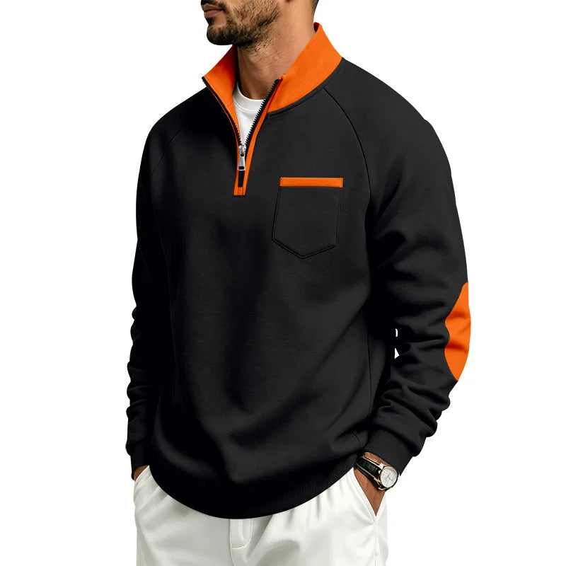 Man wearing a black quarter-zip pullover with an orange collar, pocket trim, and arm panels.