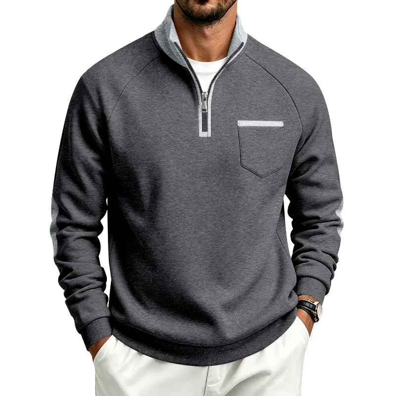 Man wearing a dark gray quarter-zip pullover with light gray collar, chest pocket detail, and sleeve stripes.