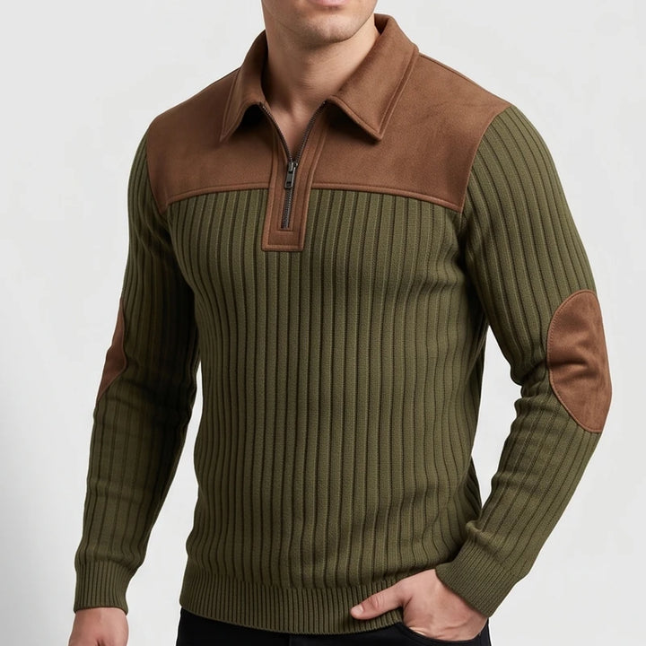 Man wearing a ribbed olive green quarter-zip sweater with brown faux suede collar, shoulder yoke, and elbow patches.