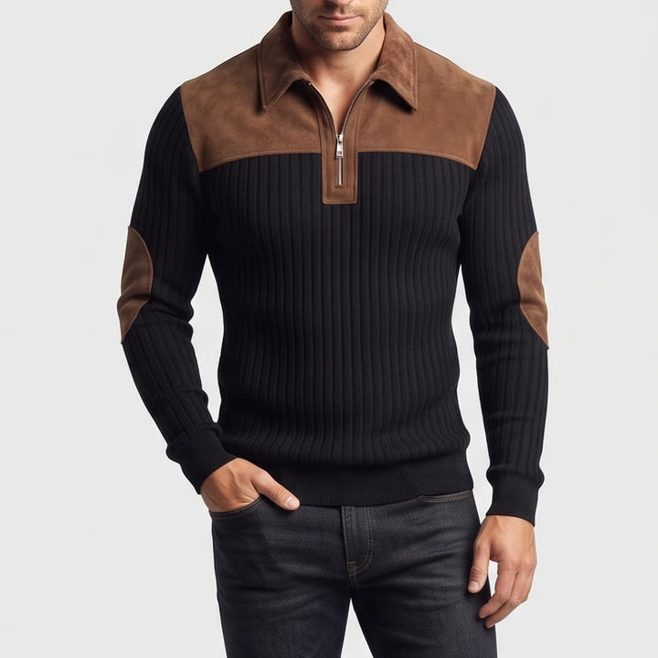 Man wearing a fitted black ribbed knit sweater with brown suede collar, quarter-zip, and elbow patches, hand in pocket.