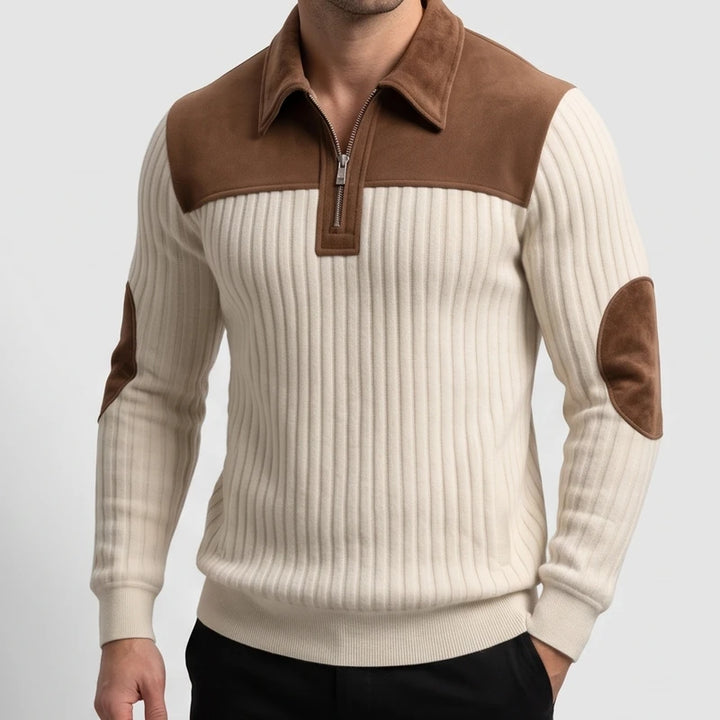 Man wearing a cream ribbed knit quarter-zip sweater with brown suede shoulder panels, collar, and elbow patches.