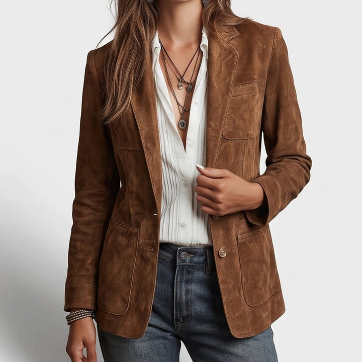 Woman wearing a brown blazer with a single button closure, patch pockets, over a white shirt and blue jeans.