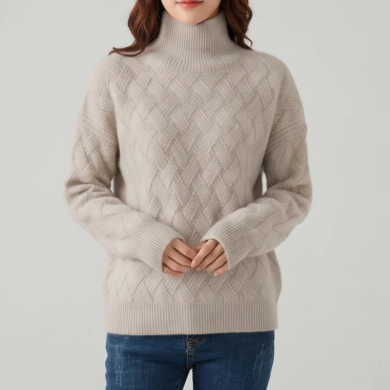 Woman wearing a beige knit turtleneck sweater with a textured crisscross pattern and ribbed trim, paired with blue jeans.