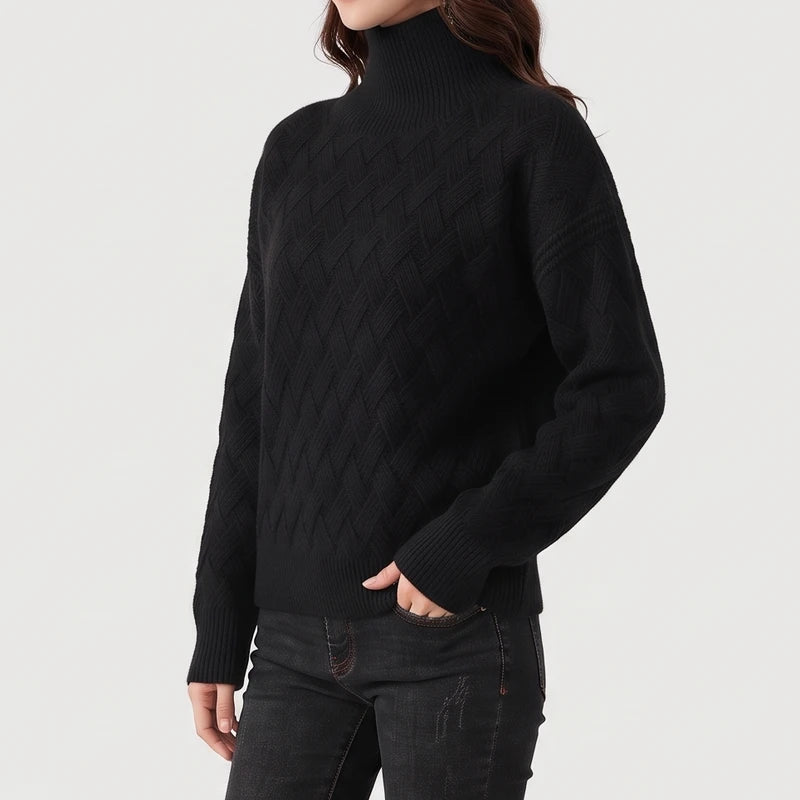 Woman wearing a black textured knit turtleneck sweater paired with dark jeans against a plain background.