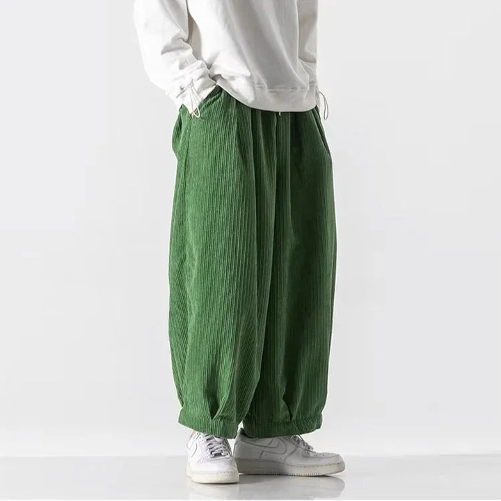 Oversized green corduroy pants with deep pleats and elastic waistband for a relaxed fit and effortless movement.