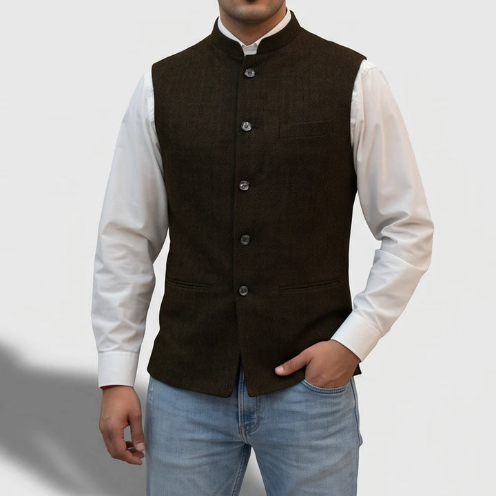 Man wearing a dark brown button-down vest with a mandarin collar over a white shirt and light wash jeans.