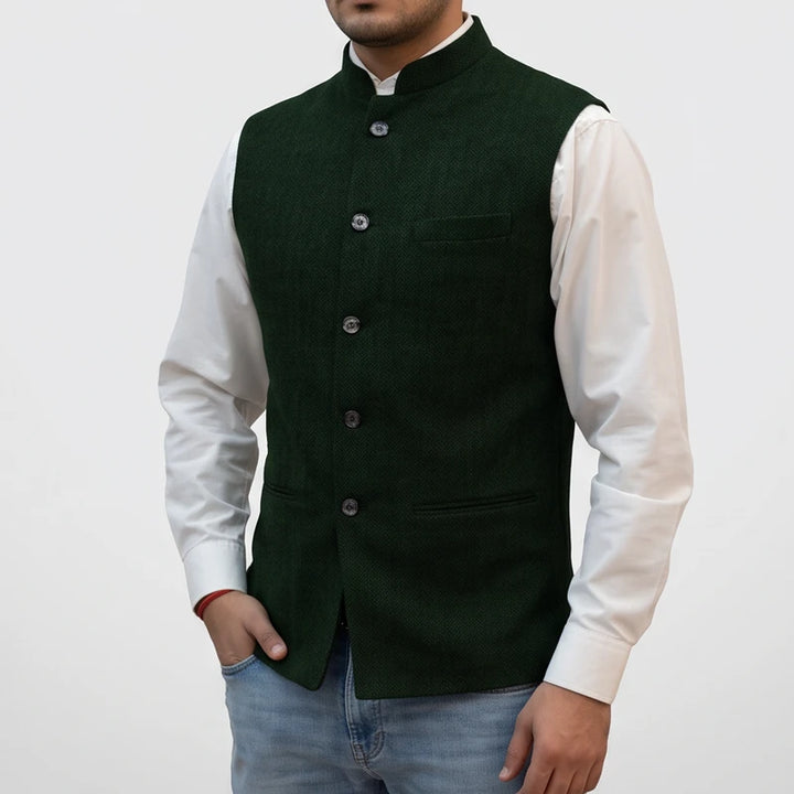 Man wearing a dark green button-front vest with a mandarin collar over a white long-sleeve shirt and jeans.