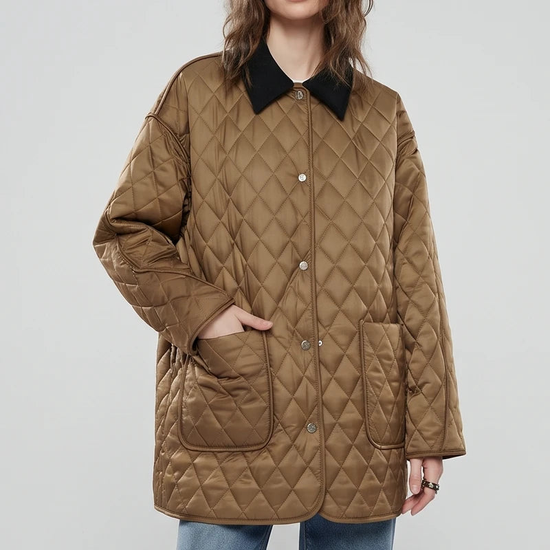 Woman wearing a long, oversized brown quilted jacket with a contrasting black collar, her hand in a patch pocket.