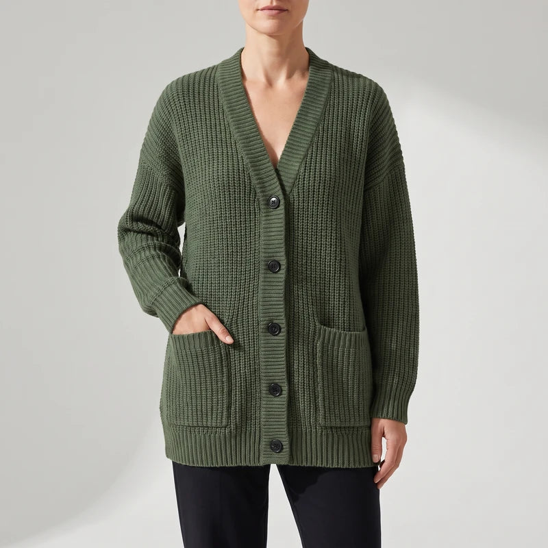Green knit cardigan on an off-gray studio background