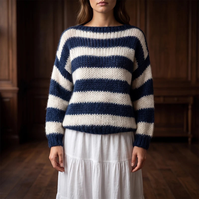 Woman wearing a relaxed-fit navy and cream striped knit sweater with a boat neck over a white tiered skirt.