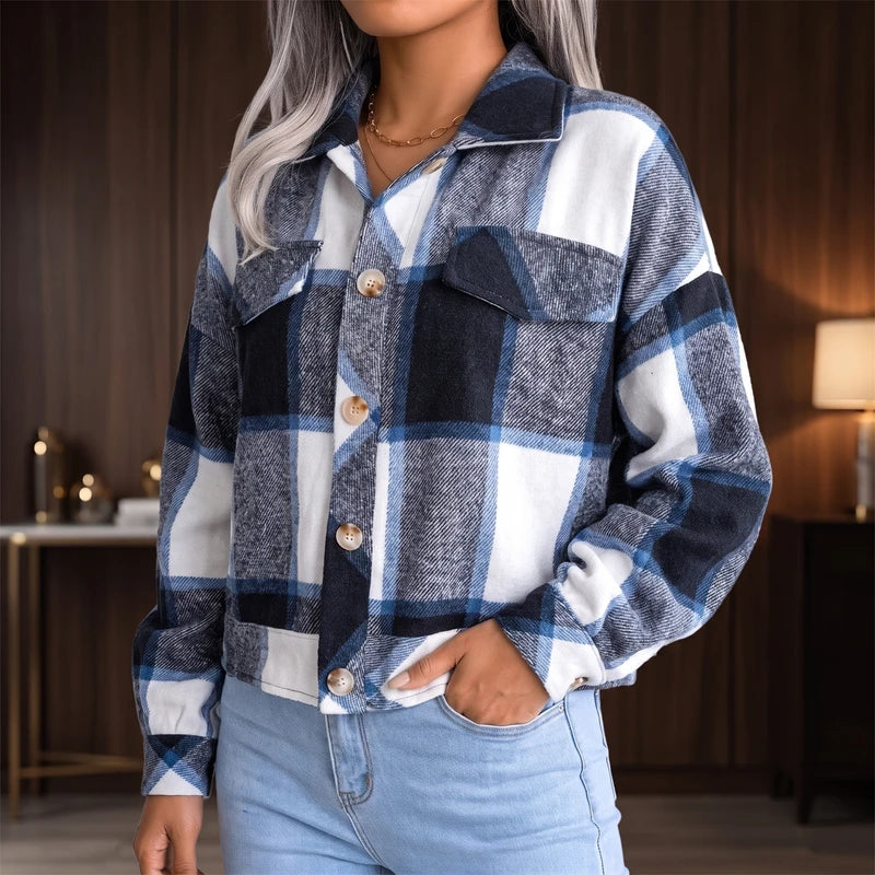 Woman wearing a blue, white, and black plaid flannel shacket with buttons and chest pockets, paired with light wash jeans.