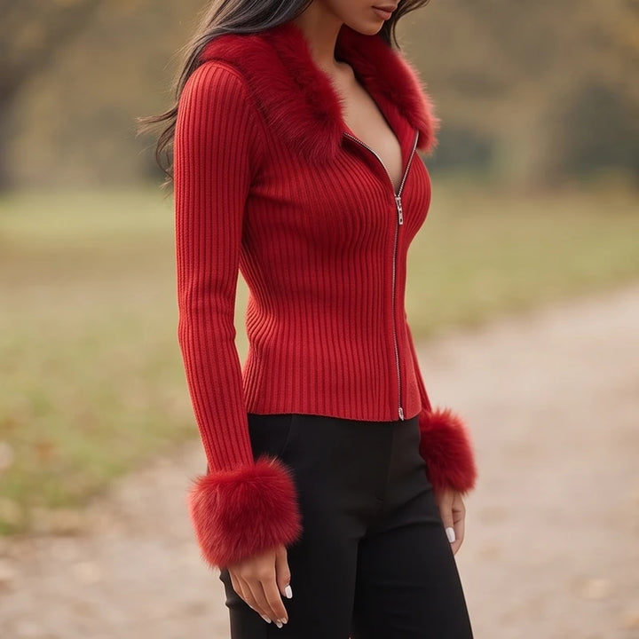Woman wearing a red ribbed knit cardigan with a furry collar and cuffs, unzipped at the top, over black pants outdoors.