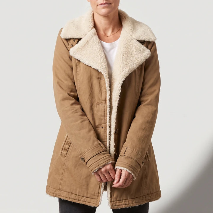Woman wearing a tan brown jacket with an open cream sherpa lining, button closure, and buttoned cuff straps.