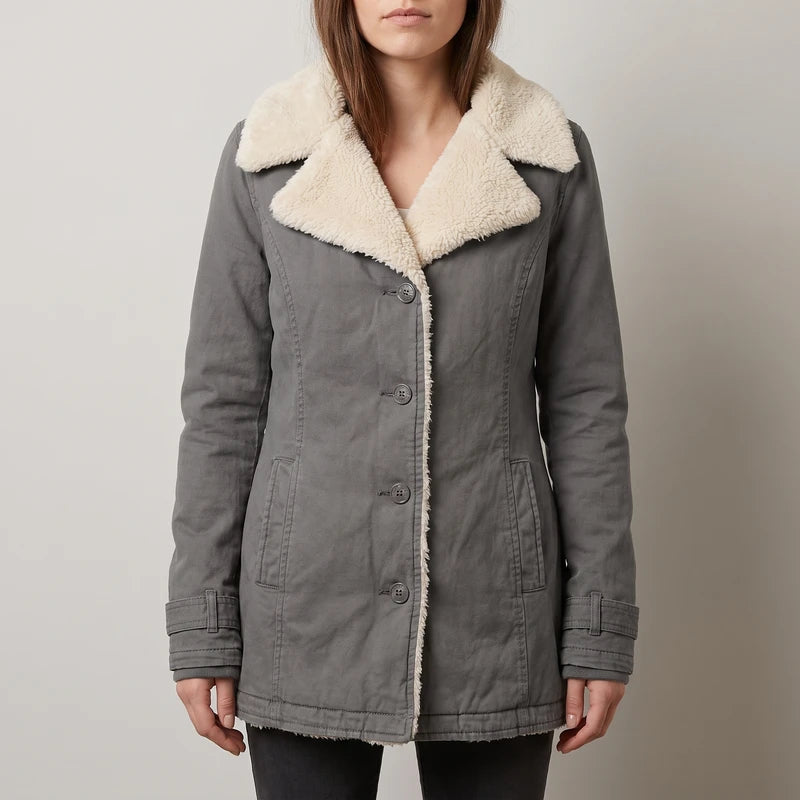 Woman wearing a long-sleeved gray coat with a cream sherpa collar and lining, featuring front buttons and pockets.