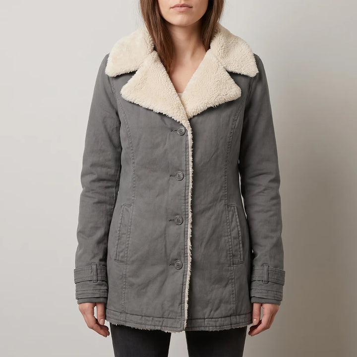 Woman wearing a long-sleeved gray coat with a cream sherpa collar and lining, featuring front buttons and pockets.