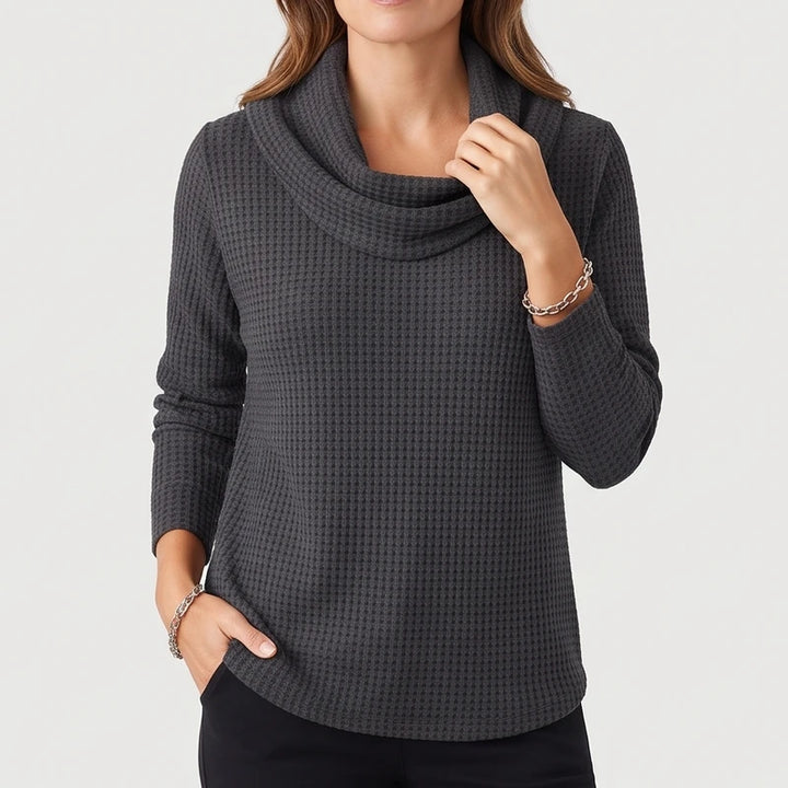 Woman wearing a dark gray waffle knit cowl neck sweater with a curved hem, posed against a plain white background.