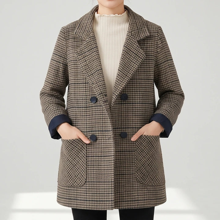 Woman wearing a brown and black plaid double-breasted blazer with dark buttons and patch pockets, hands in pockets.