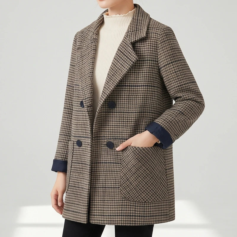 Woman wearing a brown and black houndstooth pattern double-breasted blazer with dark buttons and patch pockets, over a cream turtleneck.