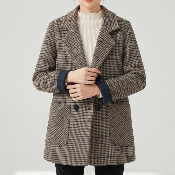 Woman wearing a brown and black plaid blazer with dark cuffs, a cream ribbed sweater, and black pants.