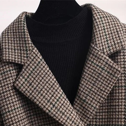 Close-up of a brown and black houndstooth pattern blazer with wide lapels over a black ribbed turtleneck top.