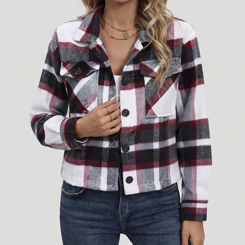 Woman wearing a cropped plaid jacket in white, black, and maroon, with dark buttons and chest pockets, over blue jeans.