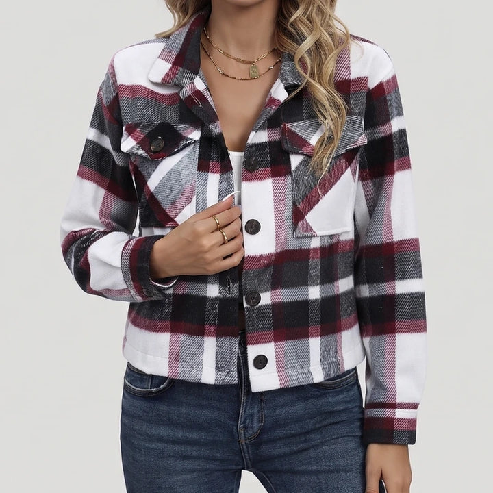 Woman wearing a cropped plaid jacket in white, black, and maroon, with dark buttons and chest pockets, over blue jeans.