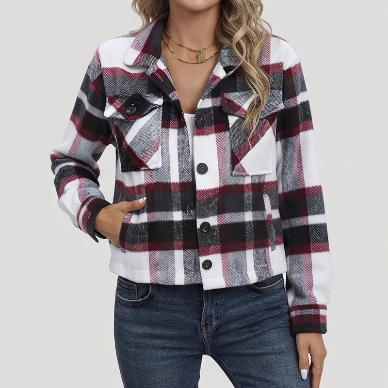 Woman wearing a white, black, and maroon plaid shirt jacket with large flap pockets over a white top and blue jeans.