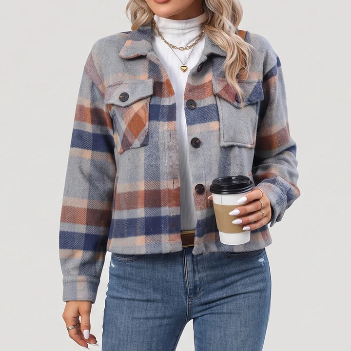 Woman wearing a relaxed-fit grey, orange, and blue plaid shirt jacket over a white top, holding a coffee cup.