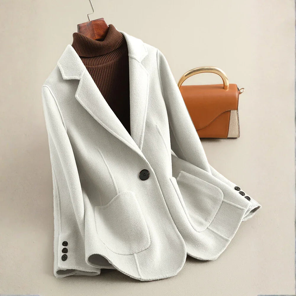 Light grey blazer-style coat with large lapels, a single dark button, and curved patch pockets.