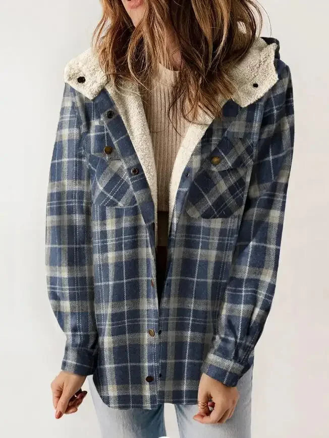 Woman wearing a blue and grey plaid hooded jacket with a cream sherpa lining and brass snaps, over a beige top.