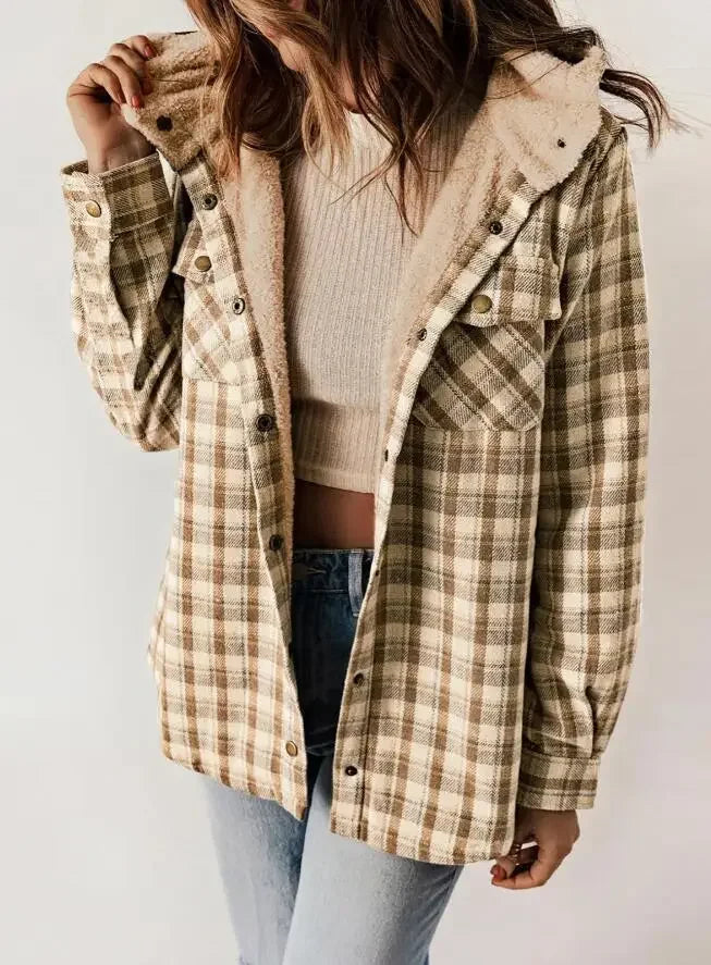 Woman wearing an unbuttoned tan and brown plaid jacket with a cream sherpa-lined hood and interior over a ribbed top.