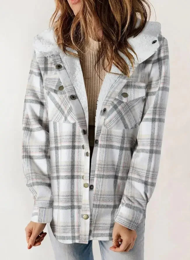 Woman wearing an open, hooded plaid jacket in white, gray, and subtle pink over a tan ribbed top, with faux shearling lining.