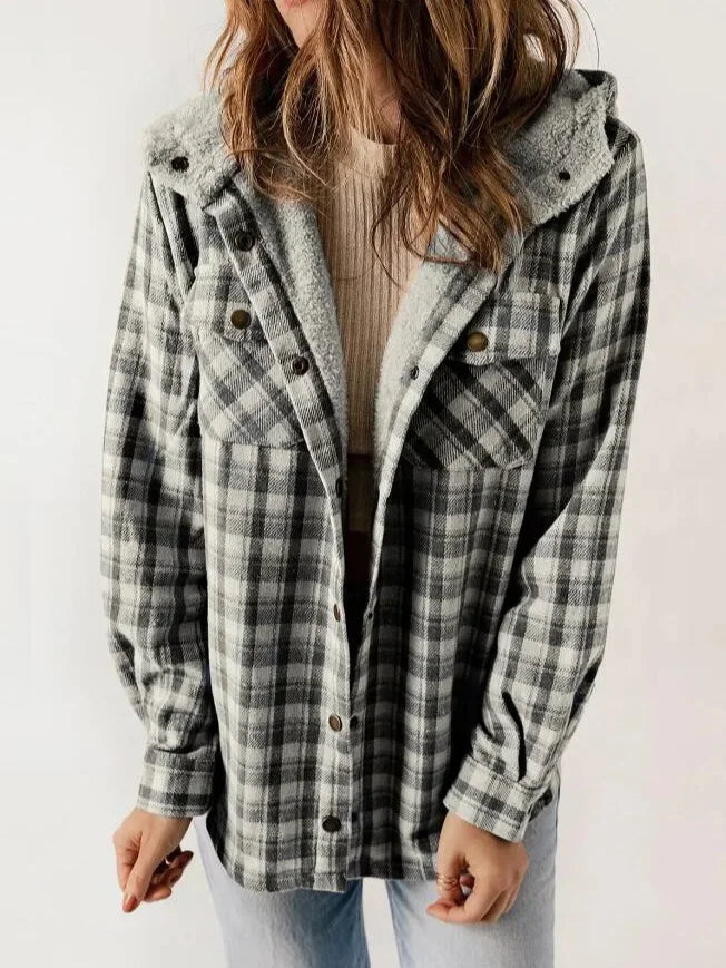Woman wearing an open gray and black plaid jacket with a sherpa-lined hood over a ribbed beige top.
