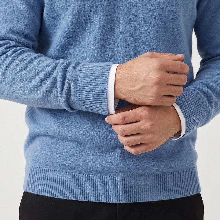 Man wearing a light blue knit sweater with ribbed cuffs and hem layered over a white collared shirt.