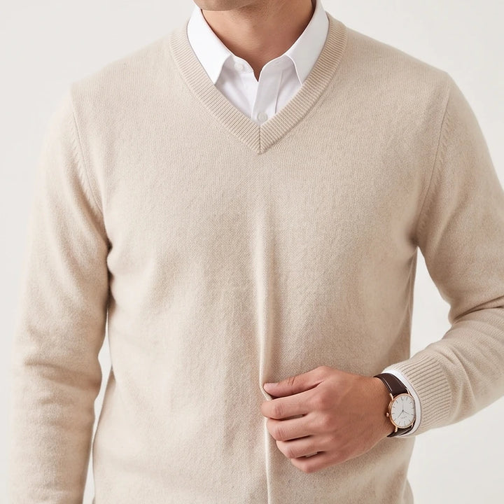 Man wearing a light beige v-neck wool sweater layered over a crisp white collared shirt.