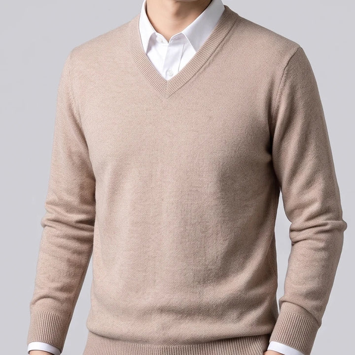 Man wearing a beige wool v-neck sweater with ribbed trim layered over a white collared button-down shirt.